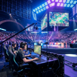 Arena Esports World Cup 2026 w Paryżu. Gracz przy stanowisku, kamery telewizyjne i tłum kibiców w neonowym świetle podczas transmisji e-sportowej na żywo.