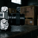 Aparat Fujifilm X-T6 retro na ciemnym blacie. Rozmyte tło oznacza błędy autofokusa i opóźnione dostawy. Polska i świat, nowoczesne gadżety fotograficzne.
