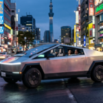 Srebrna Tesla Cybercab bez kierownicy w świetle neonów. Futurystyczny, aerodynamiczny profil i minimalistyczne wnętrze. Motoryzacja – Polska i świat.