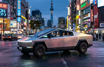 Srebrna Tesla Cybercab bez kierownicy w świetle neonów. Futurystyczny, aerodynamiczny profil i minimalistyczne wnętrze. Motoryzacja – Polska i świat.