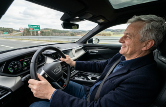 Uśmiechnięty 57-letni Polak kieruje elektrycznym Audi na pustej drodze szybkiego ruchu. Polska i świat: zadowolony kierowca wygodnie oparty plecami o fotel.