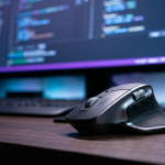 Ergonomiczna mysz Logitech MX Master 4 na ciemnym biurku, w tle kod na ekranie. Komputery, AI i oprogramowanie dla programistów, Polska i świat.